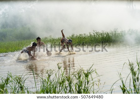 Bac Ninh, Vietnam - May 29, 2016: Children catching fish by fishing bamboo trap - the old traditional way, on pond in Bac Ninh province, with smoke from rice straw burning.