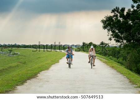 Bac Ninh, Vietnam - May 29, 2016: Two men cycling on dyke by Cau river in Bac Ninh province