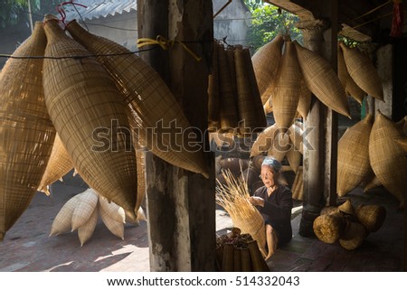 Hung Yen, Vietnam - July 9, 2016: Old house yard with many bamboo fish trap and female craftsman making traditional bamboo fish trap at her old house in Thu Sy trade village
