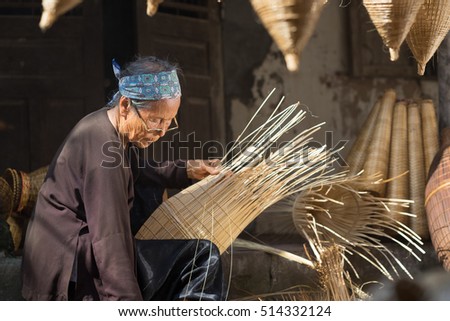 Hung Yen, Vietnam - July 9, 2016: Female craftsman making traditional bamboo fish trap at her old house in Thu Sy trade village