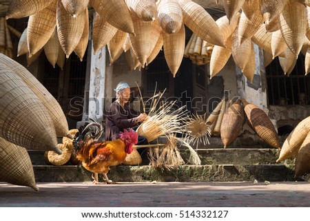 Hung Yen, Vietnam - July 9, 2016: Old house yard with many bamboo fish trap, a cock, and female craftsman making traditional bamboo fish trap at her old house in Thu Sy trade village