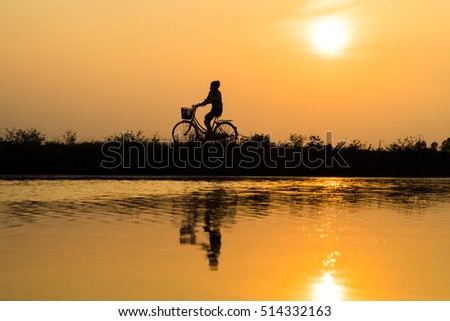 Hung Yen, Vietnam - July 9, 2016: Vietnamese rural countryside sunset scene with silhouette farmers carrying bamboo fish traps home in Thu Sy village