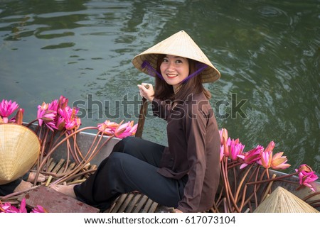 Ninh Binh, Vietnam - Oct 9, 2016: Portrait Vietnamese girl sits on boat wearing conical hat, in Yen stream