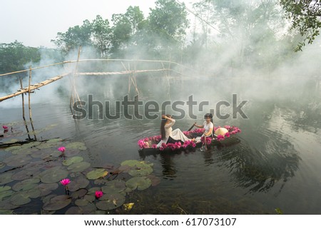 Ninh Binh, Vietnam - Oct 9, 2016: River scene with smoke, a boat carrying girls wearing traditional dress Ao Dai, conical hat, and flower, in Yen stream