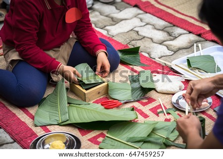 Child wear traditional dress Ao Dai learning to make Chung cake by hands closeup, Chung cake is the most important traditional Vietnamese lunar New Year (Tet) food.