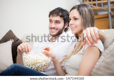 https://thumb1.shutterstock.com/display_pic_with_logo/210376/147144560/stock-photo-young-couple-eating-popcorn-while-watching-a-movie-147144560.jpg