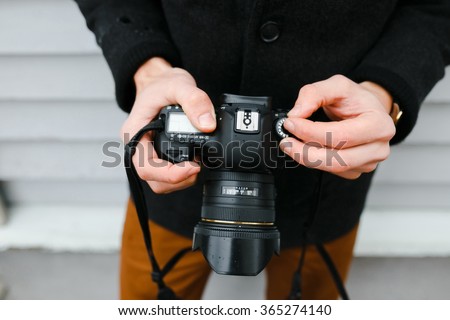 A professional photographer adjusts the camera before shooting, hands, camera, background