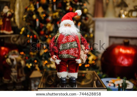 Porcelain Christmas toys in the form of Santa Claus with gift bag on the glittering indoors background