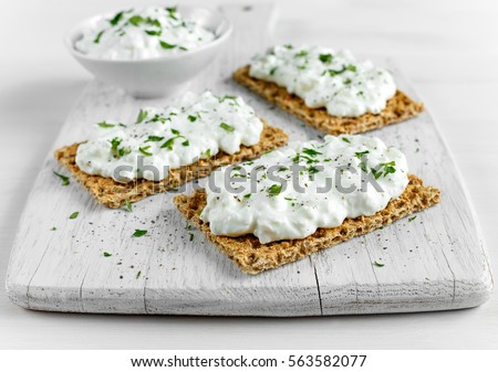 Homemade Crispbread toast with Cottage Cheese and parsley on white wooden board.