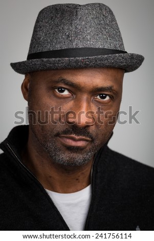 stock-photo-portrait-of-a-black-man-with-a-stubble-beard-and-a-mustache-wearing-a-hat-and-black-cardigan-241756114.jpg