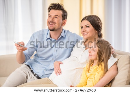 https://thumb1.shutterstock.com/display_pic_with_logo/2181548/274692968/stock-photo-young-pregnant-woman-with-husband-and-little-daughter-are-watching-tv-together-274692968.jpg
