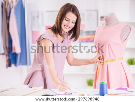 Female fashion designer taking measurement and writing it down.