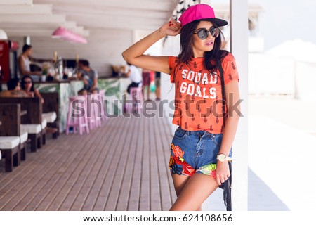 Outdoor portrait of brunette girl in stylish swag pink cap ,trendy summer outfit posing in