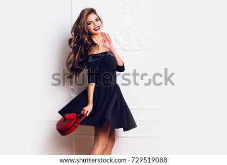https://thumb1.shutterstock.com/display_pic_with_logo/2196125/729519088/stock-photo-amazing-luxury-seductive-woman-in-stylish-black-party-dress-posing-on-white-wall-red-hand-bag-729519088.jpg