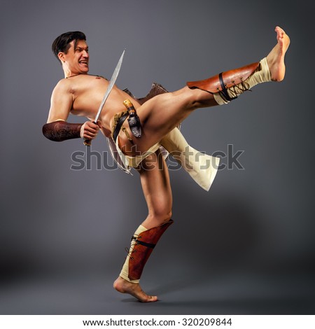 [IMAGE:https://thumb1.shutterstock.com/display_pic_with_logo/2233535/320209844/stock-photo-half-naked-man-in-the-image-of-an-ancient-warrior-strikes-his-foot-on-a-neutral-grey-background-320209844.jpg]