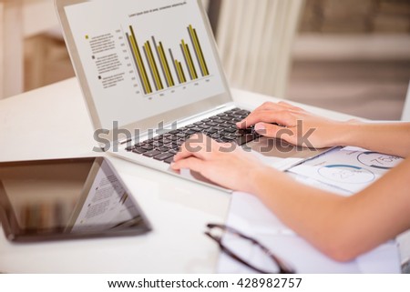 Involved in work. Pleasant person sitting at the table and using laptop while being involved in work
