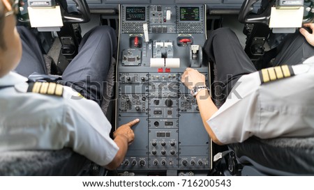 view of business jets cockpit. Two pilots operate a switches of aircraft system prior to departure.