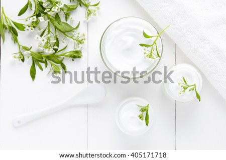 Herbal dermatology cosmetic hygienic cream with flowers skincare product in glass jar on white background