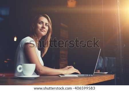 Beautiful Caucasian woman dreaming about something while sitting with portable net-book in modern cafe bar, young charming female freelancer thinking about new ideas during work on laptop computer