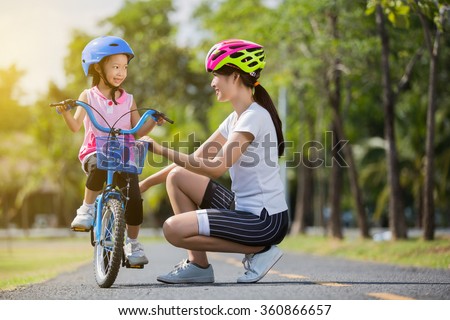 The asian family mother teaching children bicycle at the park