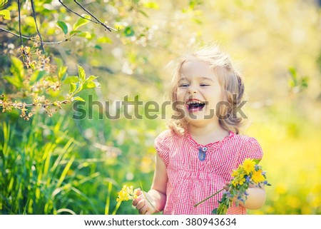 Happy little girl playing with bouquet in sunny park