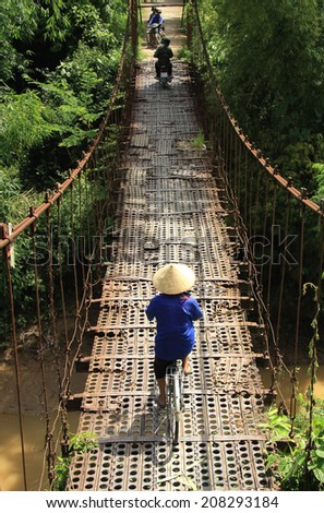 Dien Bien Phu, Vietnam July 31, 2014: Traffic on an old suspension bridge was built from the steel plate in Muong Thanh airport from the war the First Indochina.