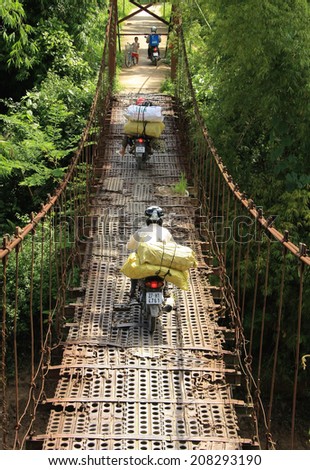 Dien Bien Phu, Vietnam July 31, 2014: Traffic on an old suspension bridge was built from the steel plate in Muong Thanh airport from the war the First Indochina.