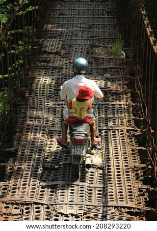Dien Bien Phu, Vietnam July 31, 2014: Traffic on an old suspension bridge was built from the steel plate in Muong Thanh airport from the war the First Indochina.