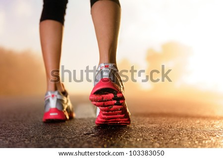 Runner feet running on road closeup on shoe. woman fitness sunrise jog workout welness concept.