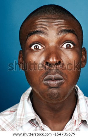 real african man silly funny face on blue background