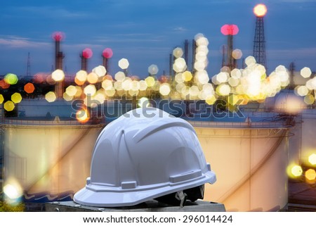 white safety helmet standing in front of oil refinery background