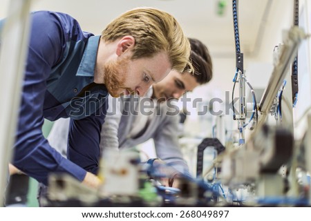 Two young handsome engineers working on electronics components and fixing broken chips