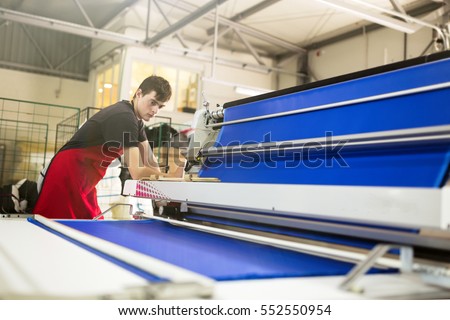 Worker working on fabric spreading machine in fabric industry