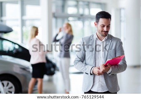 Handsome salesman at car dealership selling vehichles