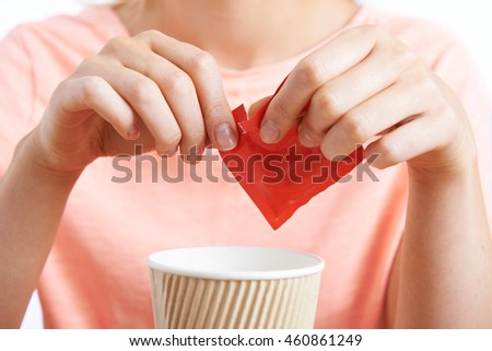 Woman Adding Artificial Sweetener To Coffee