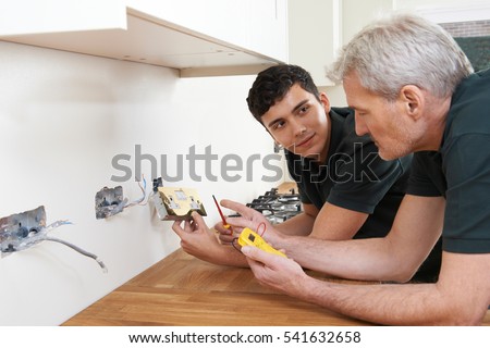 Electrician With Apprentice Working In New Home