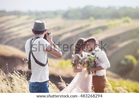 a wedding photographer takes pictures of the bride and groom in nature, the photographer in action