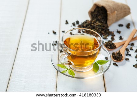 Cup of tea and leaves tea on white wooden table