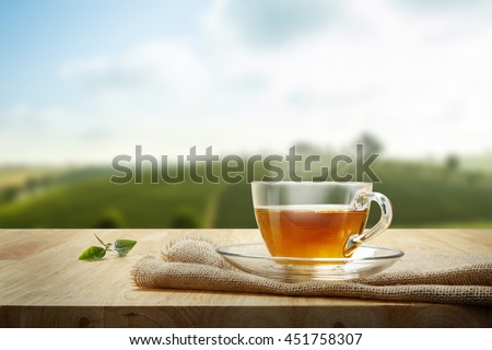 Tea cup with and tea leaf sacking on the wooden table and the tea plantations background