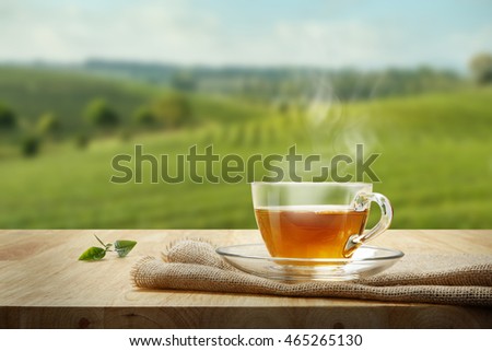 Warm cup of tea and tea leaf and sack on the wooden table and the tea plantations background