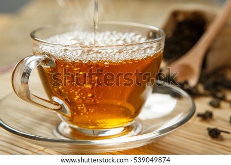 Warm cup of tea and leaves tea on wooden placemat