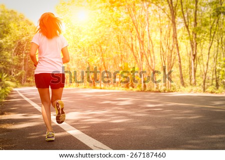 Young women running on rural road during sunset