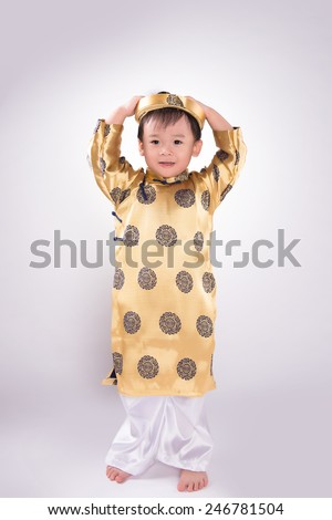 Boy in traditional Vietnamese dress. Lunar new year on white background. Happy Asian baby boy wearing Ao Dai suit in studio. Tet Holiday.