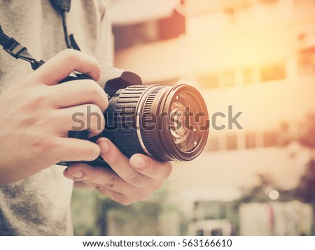 Photography or traveler Concept.The photographer hold DSRL camera in his hands with cityscape blur background and sunlight in summer time, selective focus. Photo of Vintage and filtered process.