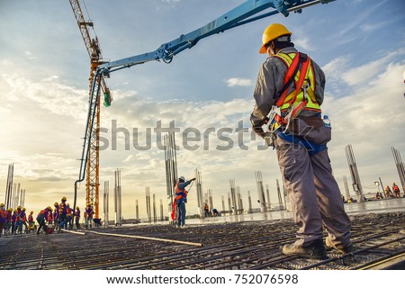 A construction worker control a pouring concrete pump on construction site and sunset background