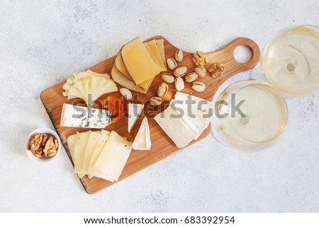 Cheese plate served with white wine, crackers and nuts, Top view. Assorted cheeses Camembert, Brie, Parmesan blue cheese, goat
