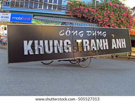 VINH, VIETNAM - MAY 29, 2015: unidentified man is carrying long signboard by tricycle in Vihn, Vietnam
