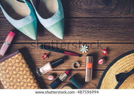 women's accessories - bag, heels, earrings, nail polish, lipstick on wooden background, top view