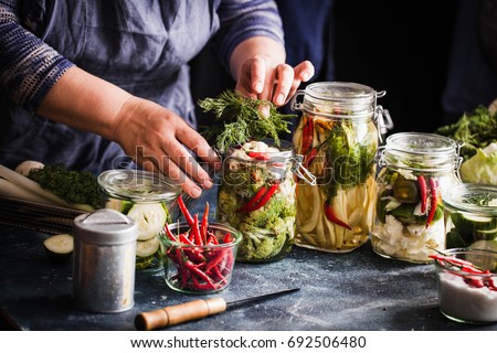 Pickled vegetables in jars displayed on table cauliflower broccoli bean cucumber green tomatoes fermented process glass jars variety copy space