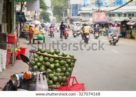 Vietnamese street hawker with a basket full of sweet oranges on bike in Ho Chi Minh city.